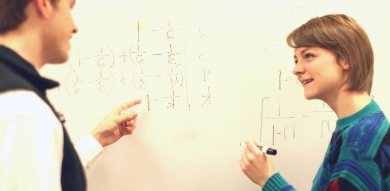 Professor and HSU solving math problems on white board