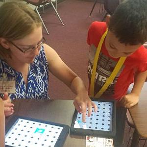 特殊教育老师向学生展示如何在iPad上玩游戏