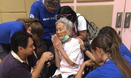 在宣教旅行中，PT学生与一位女士一起祷告.