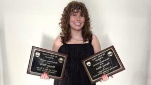 Marissa posing with two of her awards: The Dr. Jodie McGaughey Outstanding Accounting Student Award, and the Ruby A. and Jesse N. Fletcher Outstanding Student Award.